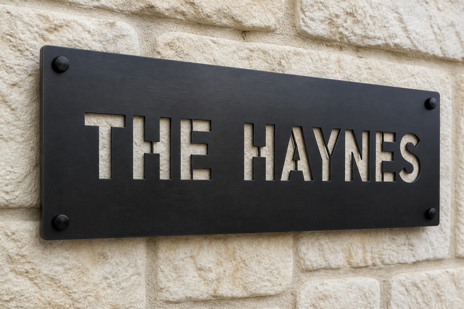 Black steel family name plate reading THE HAYNES, stencil-cut, mounted on limestone with corner standoffs
